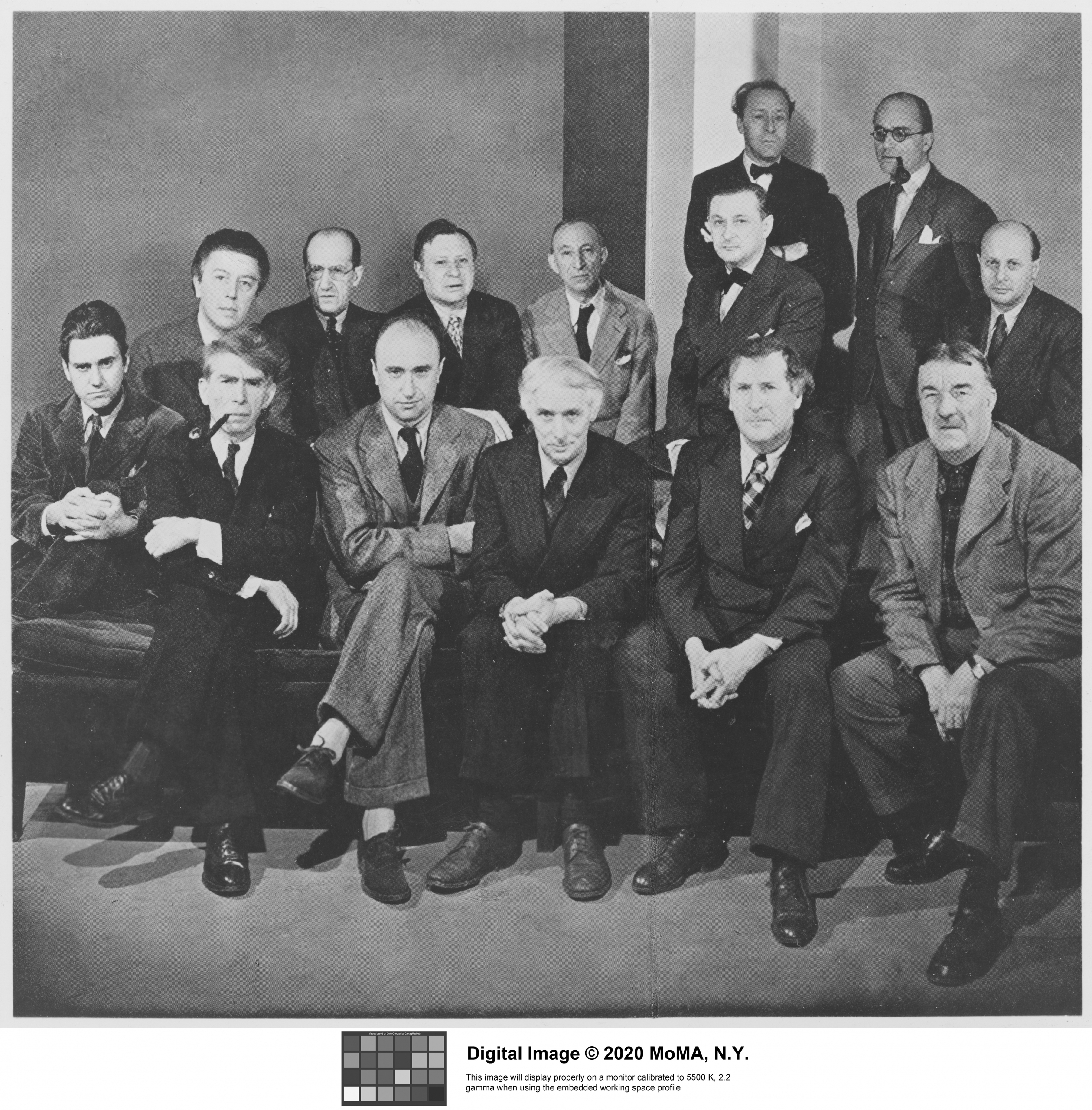 Archival photo of 14 men wearing suits and posing for the camera. Two of the men stand behind the others who are sitting. Most men appear to be middle aged.