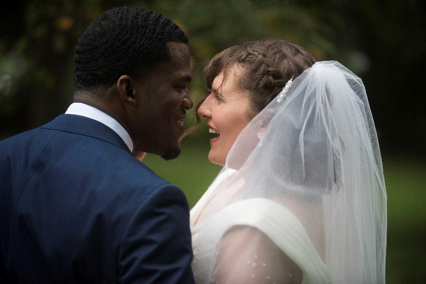 The author in her wedding dress and the groom photographed from the back, facing one another and smiling.